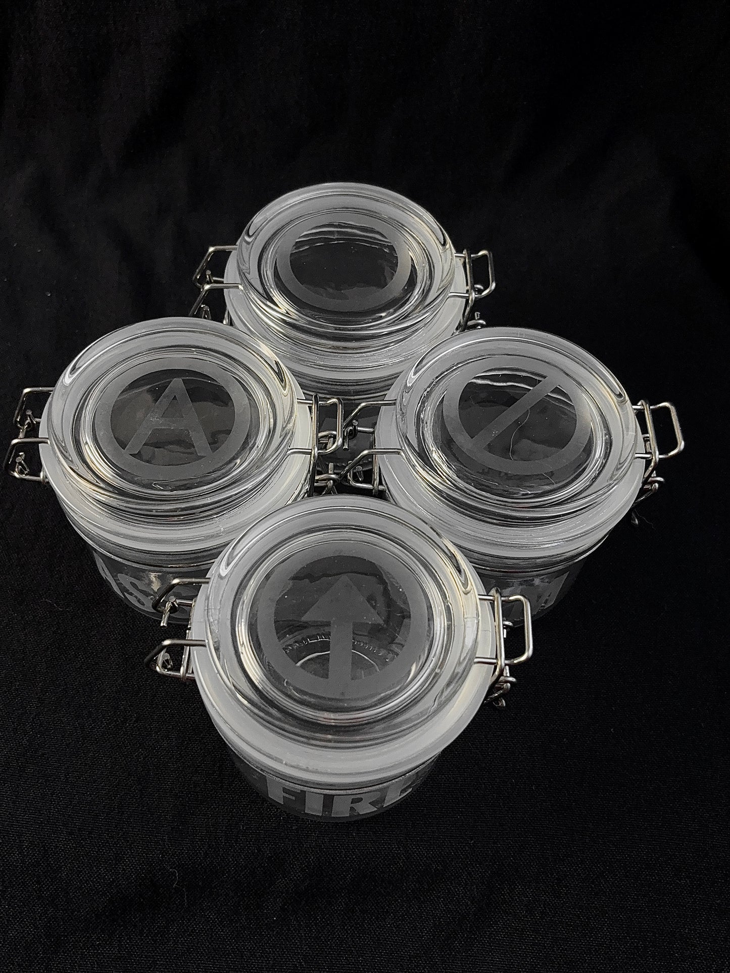 Four glass jars with metal clamps on a black background